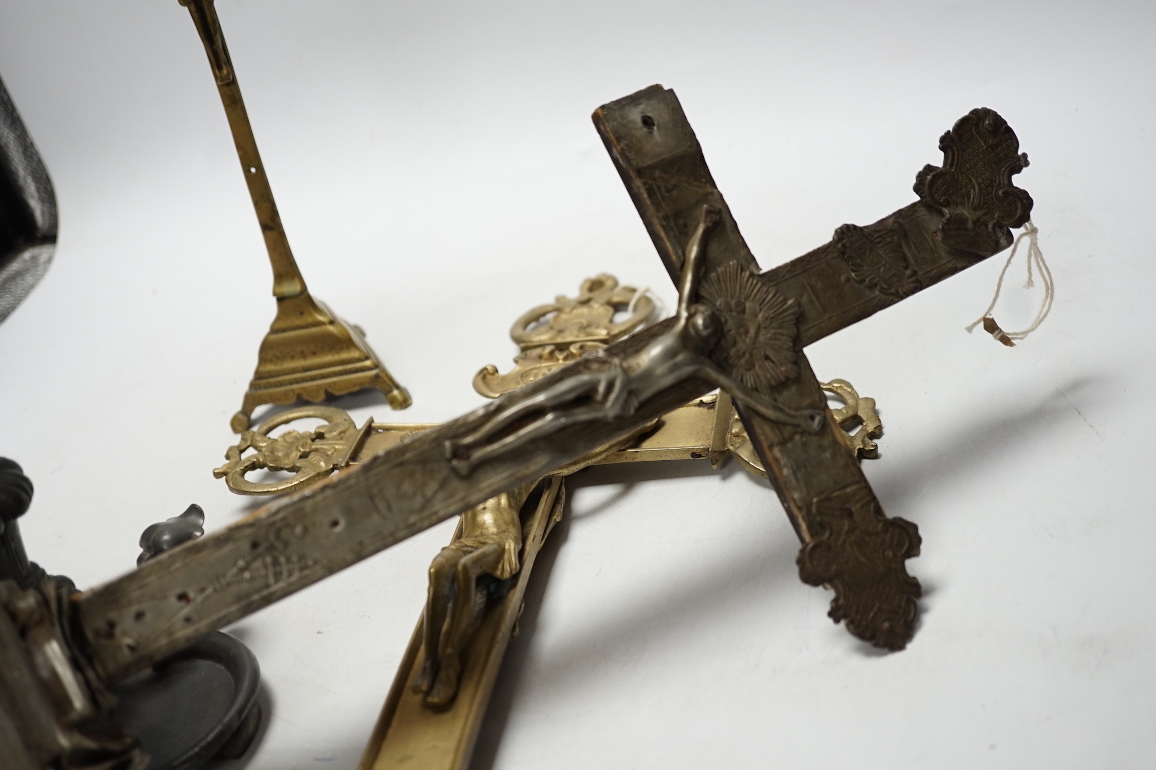 Three brass crucifixes and an Orivit pewter candlestick, tallest 45cm high